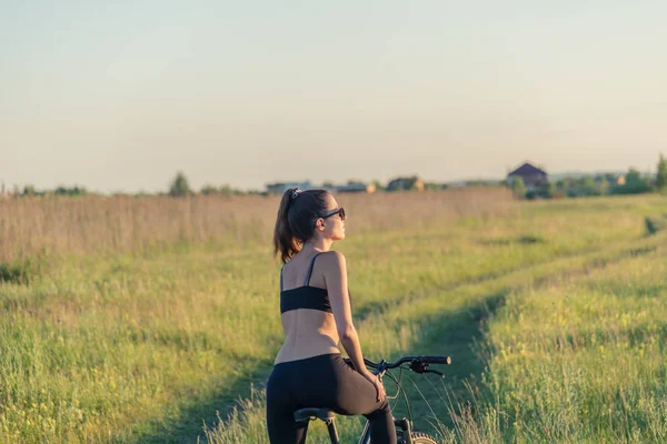 Chica montando una bicicleta de montaña en el campo — Foto de Stock