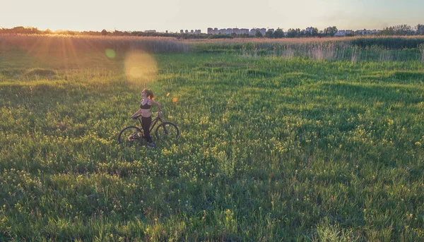 Ragazza in sella a una mountain bike nel campo — Foto Stock