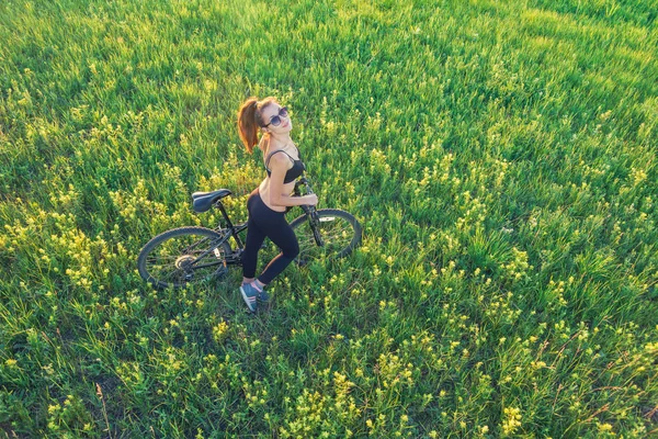 Chica montando una bicicleta de montaña en el campo — Foto de Stock