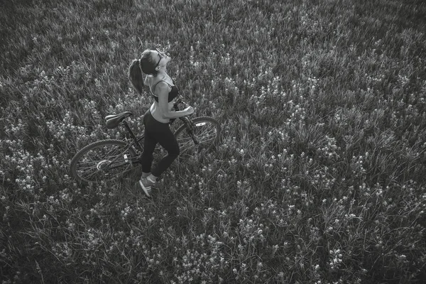 Dívka na koni na horském kole v poli — Stock fotografie