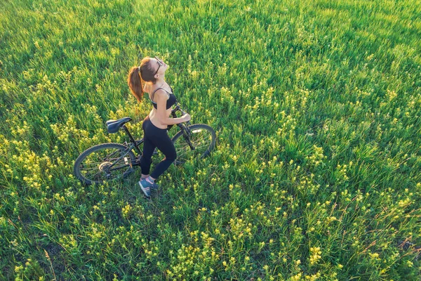 Meisje met een bergfiets in het veld — Stockfoto