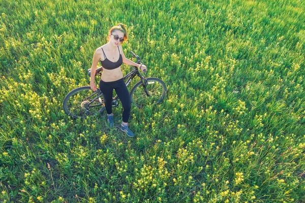 Дівчина катається на гірському велосипеді в полі — стокове фото