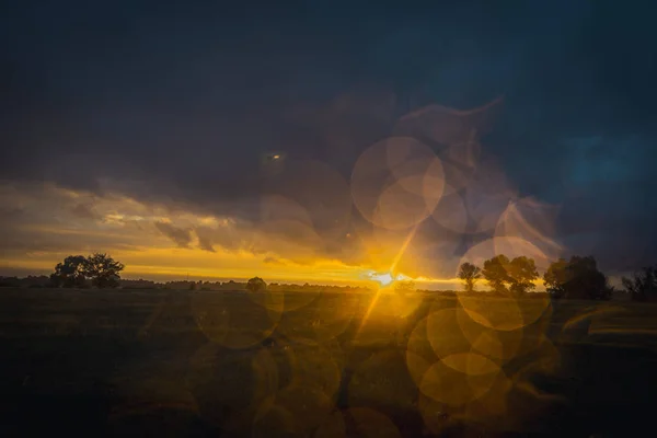 Campo. En el campo llueve y el sol se pone sobre el horizonte — Foto de Stock
