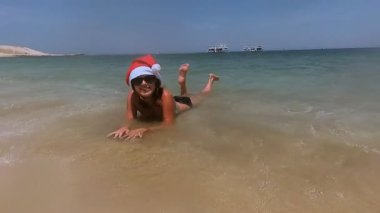 Yeni yıl. Denizin üzerinde dinlenme Noel Baba şapkalı bir kız