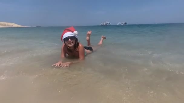 Nieuwjaar. Een meisje in een kerstman hoed rustend op de zee — Stockvideo