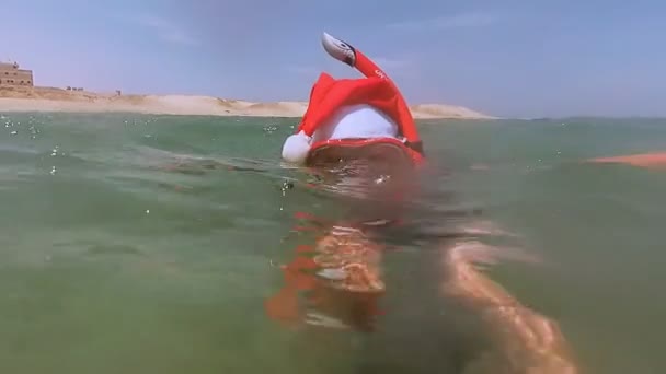 Nieuwjaar. Een meisje in een kerstman hoed rustend op de zee — Stockvideo