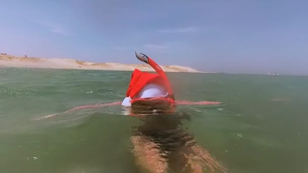 新しい年。海で休むサンタ クロースの帽子の女の子 — ストック動画