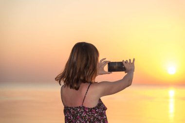 Kız bir gün batımı bir cep telefonu alıyor