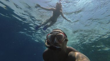 Snorkeling. Bir kız bir adamla bir maske ile denizde yüzüyor