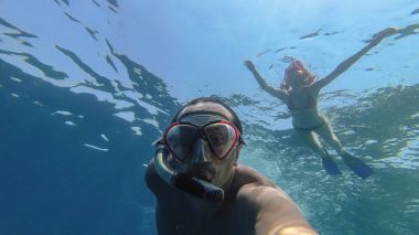 Snorkeling. Bir kız bir adamla bir maske ile denizde yüzüyor