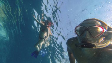 Snorkeling. Bir kız bir adamla bir maske ile denizde yüzüyor