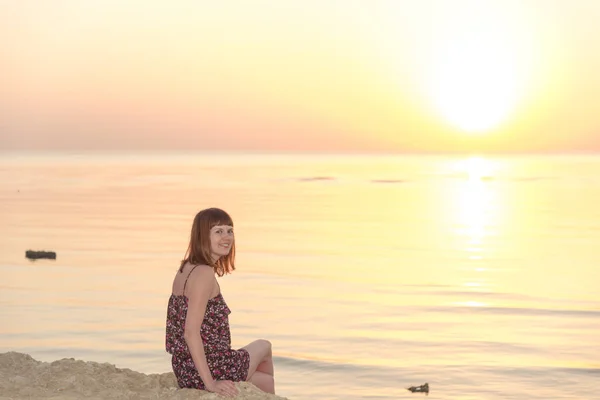 En tjej ser på gryningen av solen kommer ur havet — Stockfoto