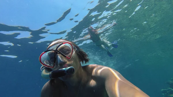 Snorkling. En fyr med en pige svømmer i havet med en maske - Stock-foto