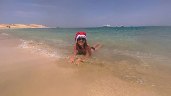 Το νέο έτος. Ένα κορίτσι σε ένα καπέλο Santa Claus αναπαύεται πάνω στη θάλασσα — Φωτογραφία Αρχείου