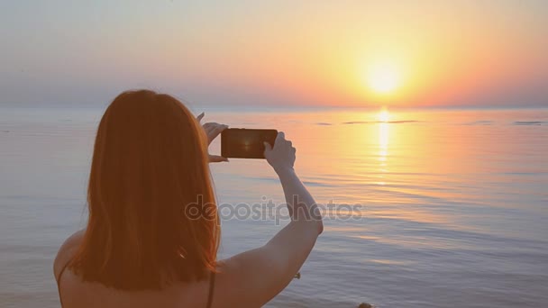 Meisje is het nemen van een zonsondergang op een mobiele telefoon — Stockvideo