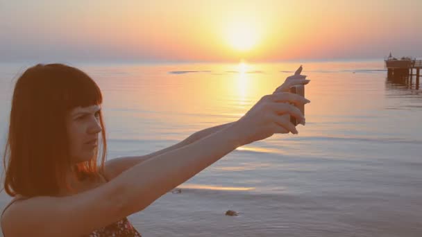 Chica está tomando un atardecer en un teléfono móvil — Vídeos de Stock