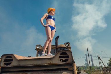 Küresel ısınma. Bir kız bir traktör üzerinde güneşlenmek bir mayo içinde.