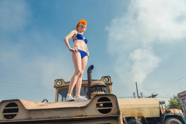 El calentamiento global. Una chica en traje de baño tomando el sol en un tractor . — Foto de Stock