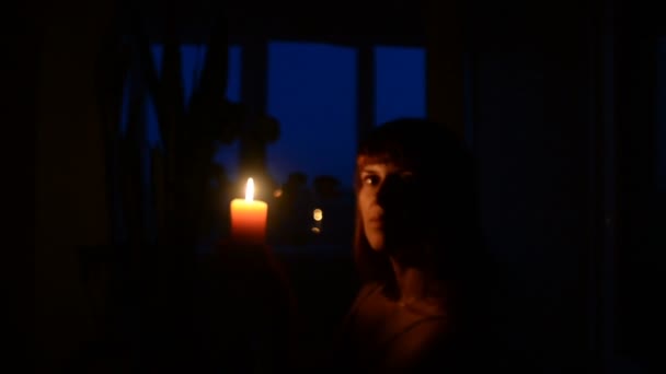 Kaars. Een meisje licht een kaars in een donkere kamer — Stockvideo