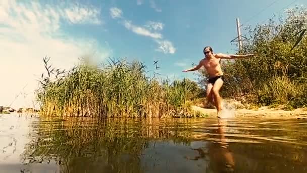 A cámara lenta. El tipo salta lentamente al lago. — Vídeo de stock
