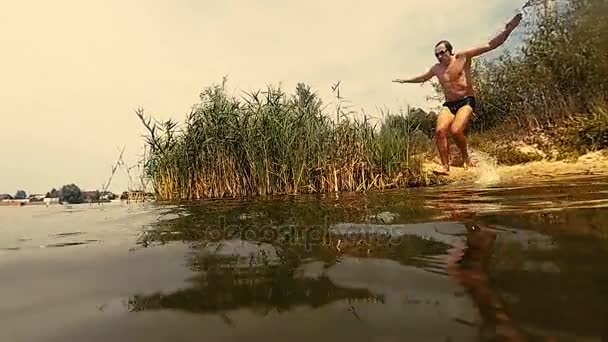 A cámara lenta. El tipo salta lentamente al lago. — Vídeos de Stock