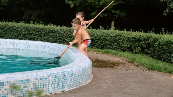 Los niños limpian la piscina de hojas — Vídeos de Stock