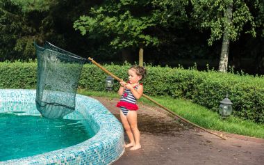 Küçük kız havuzu yapraklardan temizliyor.