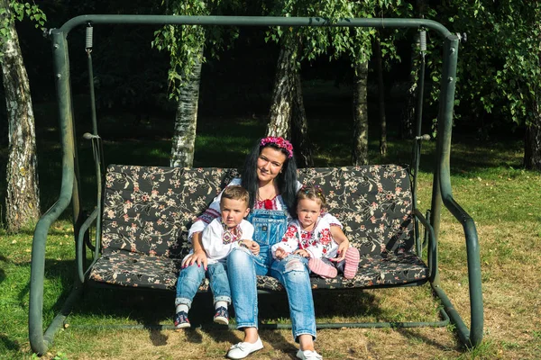 Kinderen met moeder schommel voor een schommel — Stockfoto