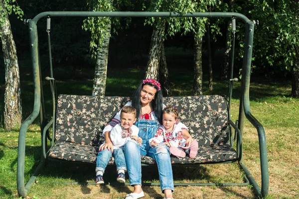 Kinderen met moeder schommel voor een schommel — Stockfoto