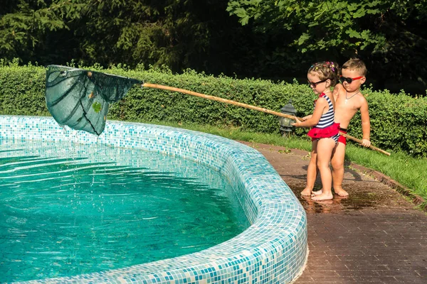 Children clean the pool of leaves