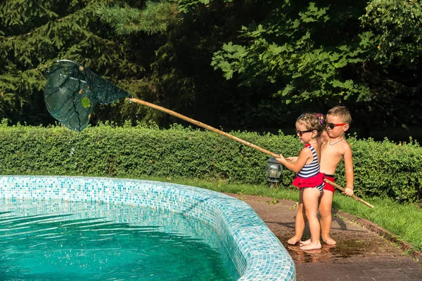 Kinderen schoon het zwembad van bladeren — Stockfoto