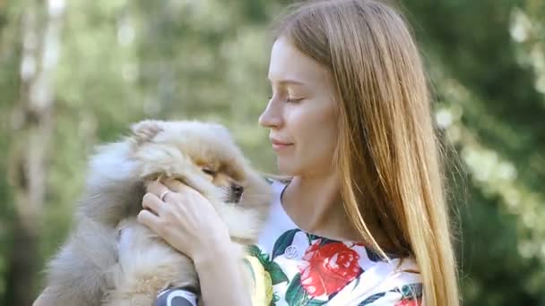 Uma menina está andando com um parque com um cachorro. Spitz da Pomerânia — Vídeo de Stock