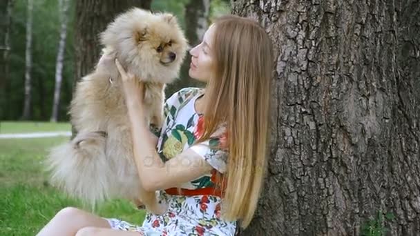 Una ragazza cammina con un parco con un cane. Spitz alla Pomerania — Video Stock