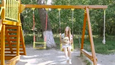Çocuk swing. Bir kızla bir salıncak üzerinde bir köpek kataetsya.