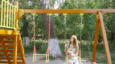Çocuk swing. Bir kızla bir salıncak üzerinde bir köpek kataetsya.
