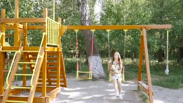 Children's swing. A girl with a dog kataetsya on a swing. — Stock Video