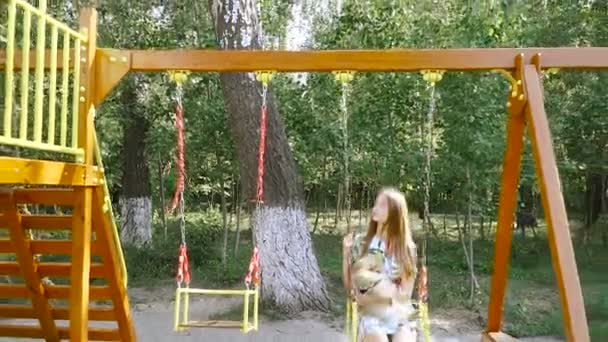 Çocuk swing. Bir kızla bir salıncak üzerinde bir köpek kataetsya. — Stok video