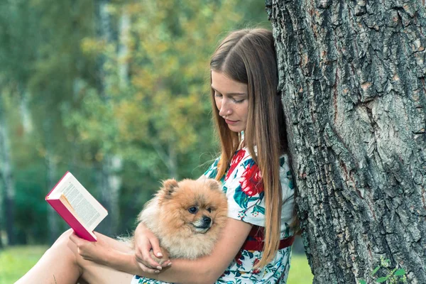 A girl is walking with a park with a dog. Pomeranian Spitz — Stock Photo, Image