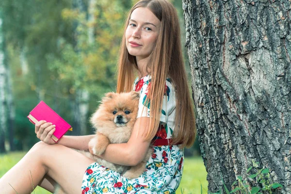 En flicka går med en park med en hund. Pomeranian Spitz — Stockfoto