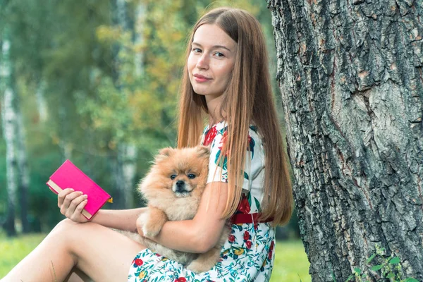 Uma menina está andando com um parque com um cachorro. Spitz da Pomerânia — Fotografia de Stock