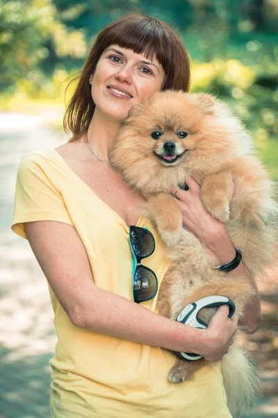 En flicka går med en park med en hund. Pomeranian Spitz — Stockfoto