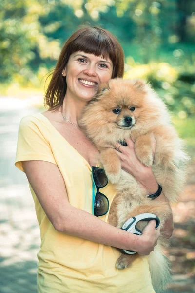 Una chica está caminando con un parque con un perro. Spitz de Pomerania — Foto de Stock