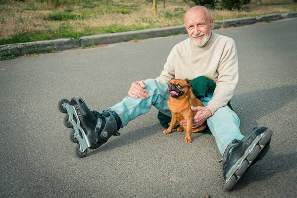 O avô rola no rolo com um cão da raça de Griffon — Fotografia de Stock