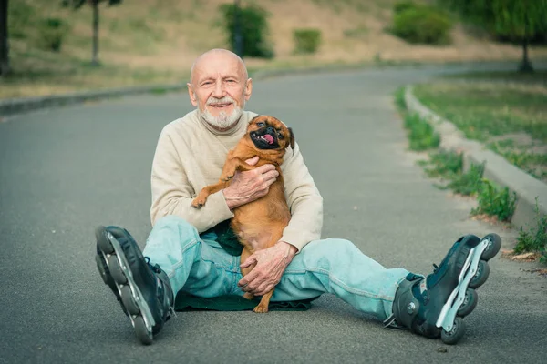 Grandpa rolls on roller with a dog of the Gryphon breed — Stock Photo, Image