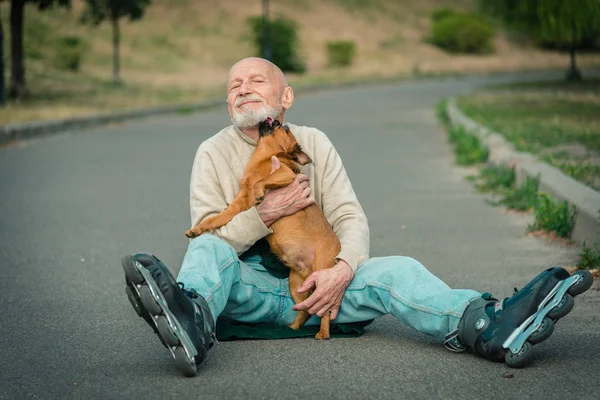 O avô rola no rolo com um cão da raça de Gryphon — Fotografia de Stock