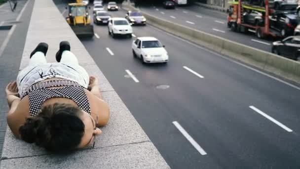 Autostrada. La ragazza è sdraiata sul marciapiede vicino all'autostrada — Video Stock