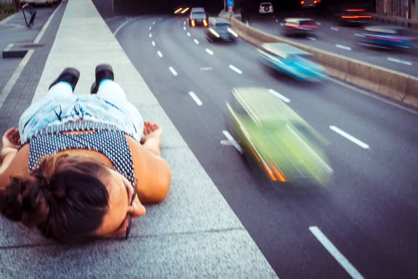 高速道路。女の子は高速道路の近くで歩道に横たわっています。 — ストック写真