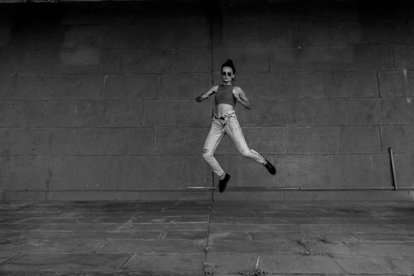 Salta. Menina pulando contra a parede cinza — Fotografia de Stock