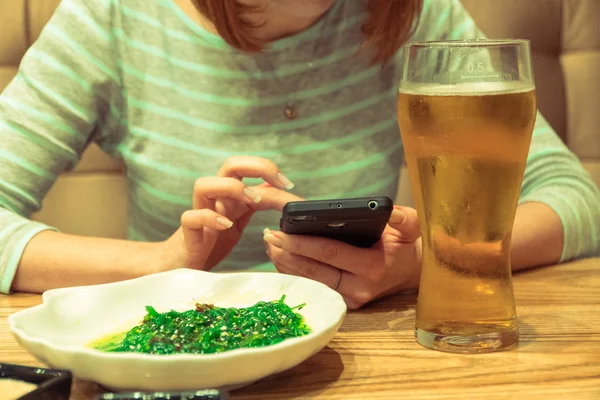 Mobiltelefon. En tjej i en bar ser ut på skärmen på en mobil ph — Stockfoto