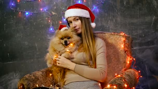 En flicka i en jul hatt med en Pomeranian Pomeranian hund — Stockvideo